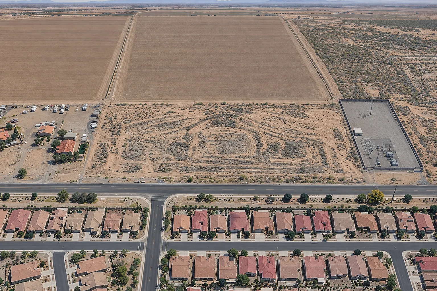 Aerial view of a vacant rectangular parcel in Casa Grande, Arizona, beside a residential street and farm fields