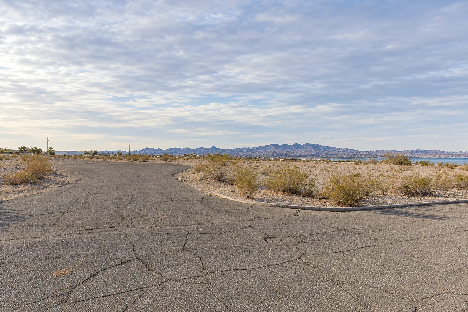 Open desert lot of gravel and creosote scrub in Lake Havasu City, with mountains across the horizon