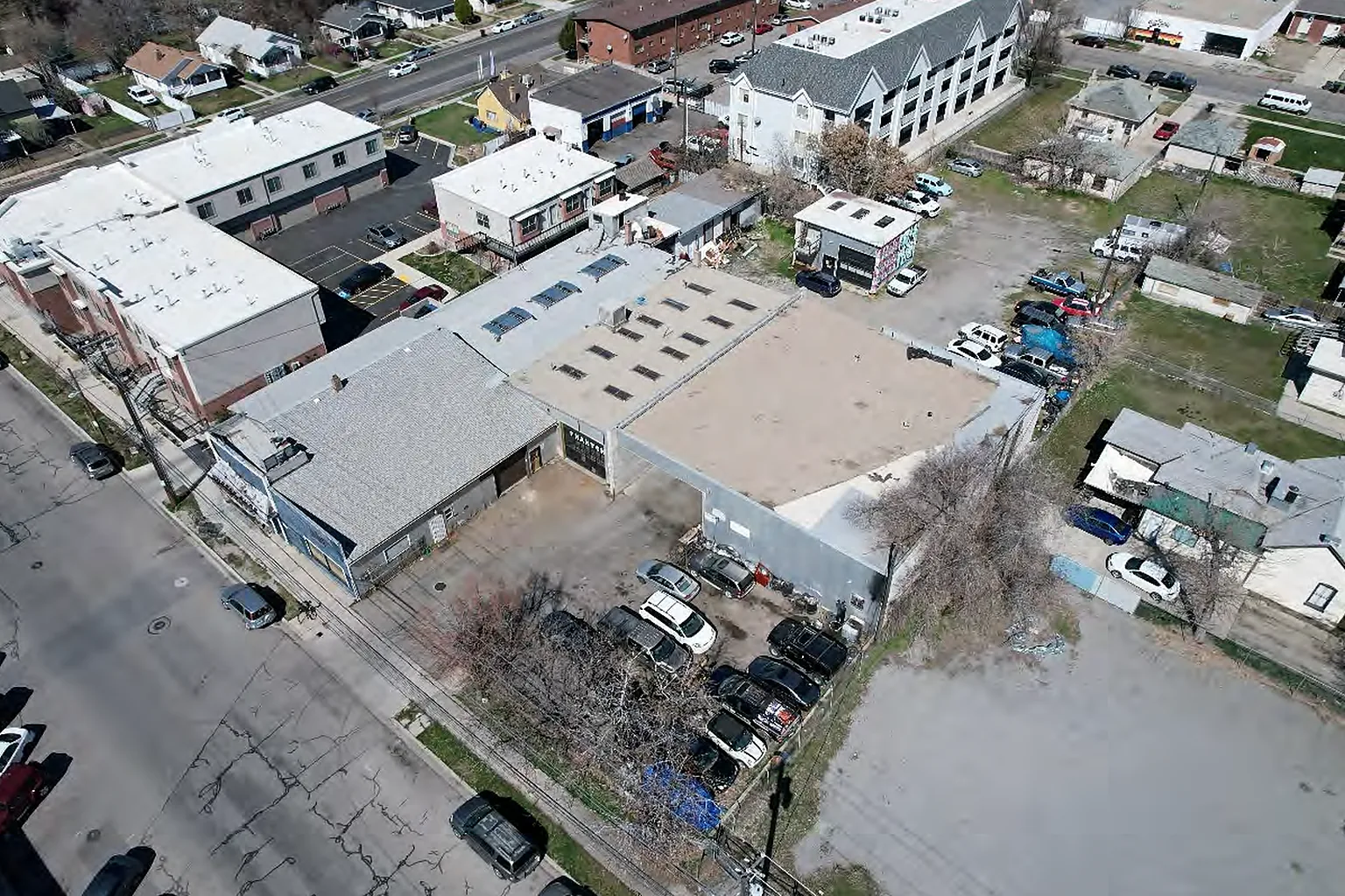 Aerial photograph of the Provo site: an existing single-story commercial building and surface parking on a downtown block